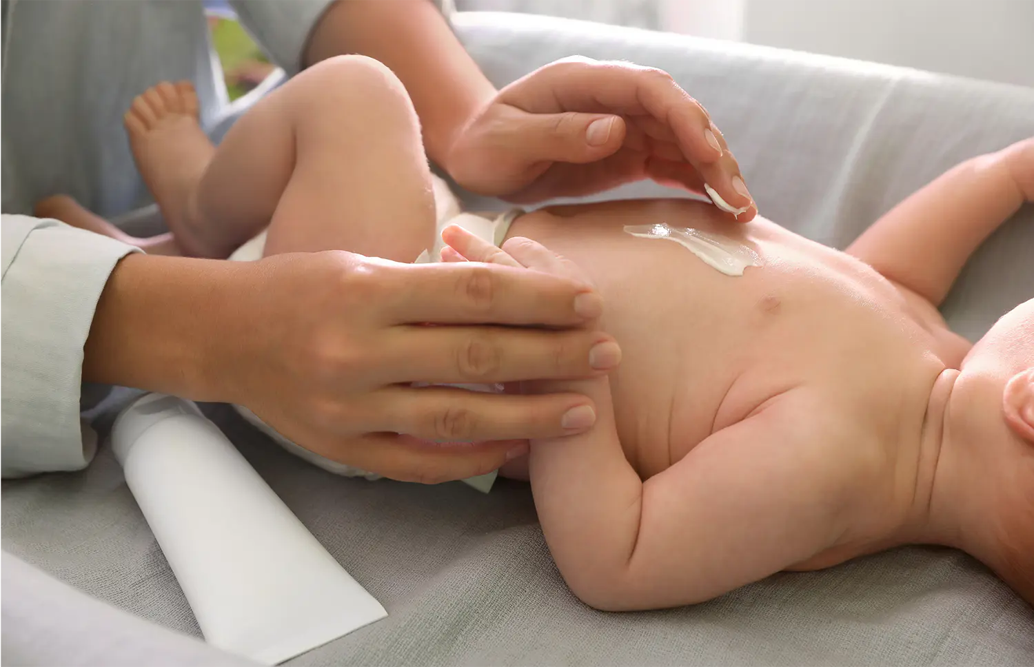 乳児の腹部に薬を塗っている写真